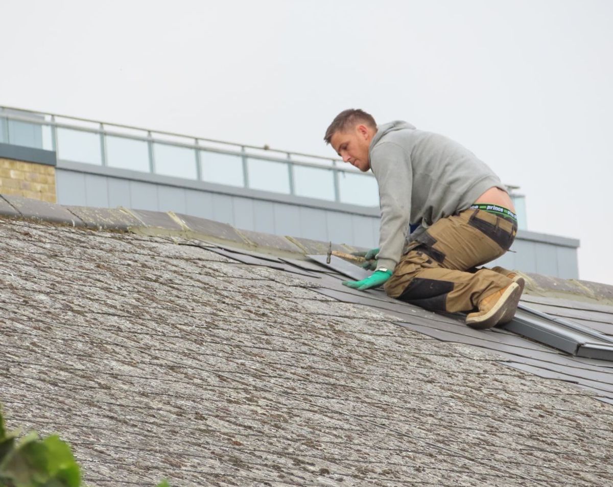 A contractor installing shingles on a residential roof